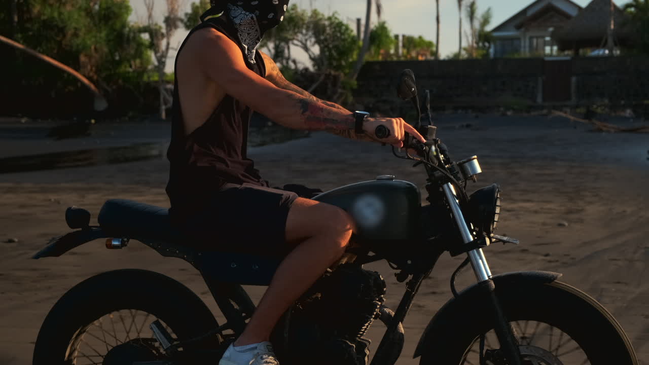 hombre montando una motocicleta en una playa al atardecer