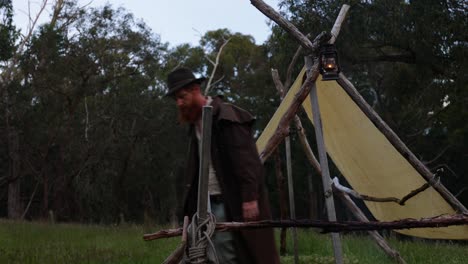 bushman hangs up a kerosene lantarn by his historical pioneer hut in the bush