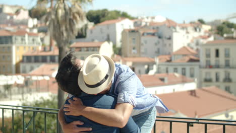 gay arrodillado, caja de apertura con anillo de compromiso frente a amante que está emocionado y lo abraza