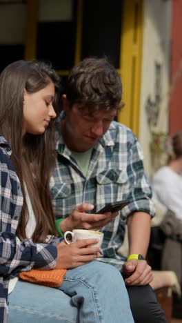 pareja disfrutando de café y un teléfono inteligente en una cafetería