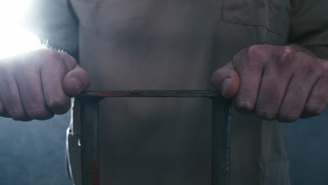 extreme close-up parallax shot of a prisoner's hands holding onto the bars of his cell