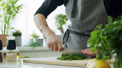 Woman-cutting-parsley-on-wooden-board