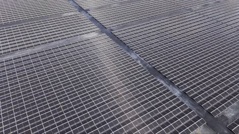Wide drone aerial perspective of a large solar farm with many aligned photovoltaic panels