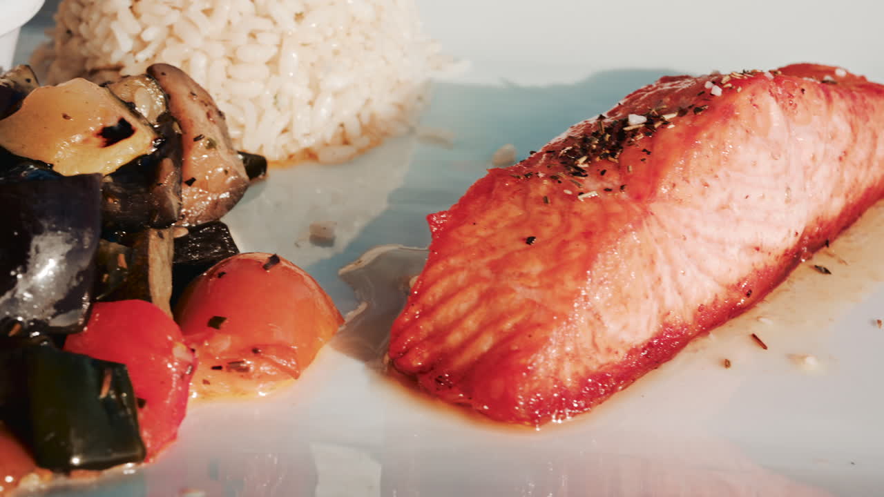 A balanced restaurant dish featuring grilled salmon fillet, white rice, lemon, and mixed vegetables