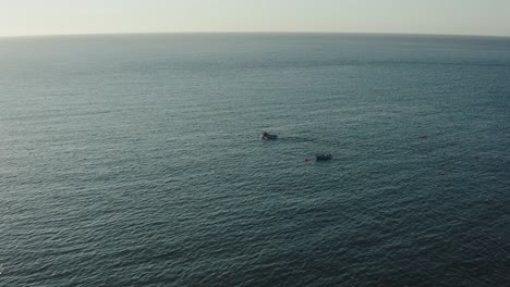 Große-Drohnenaufnahme-Eines-Fischerbootes,-Das-Im-Frühen-Morgenlicht-Aufs-Meer-Hinausfährt