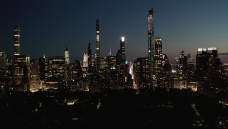 moving time lapse hyper lapse over new york city central park at night towards skyline of manhattan skyscraper with glowing city lights, aerial hyperlapse