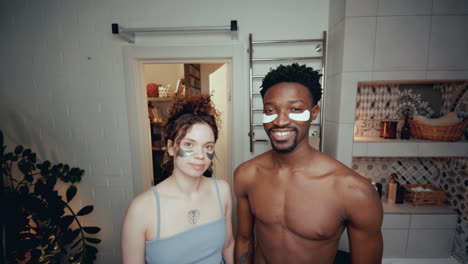 retrato de una pareja joven y diversa con parches debajo de los ojos en el baño