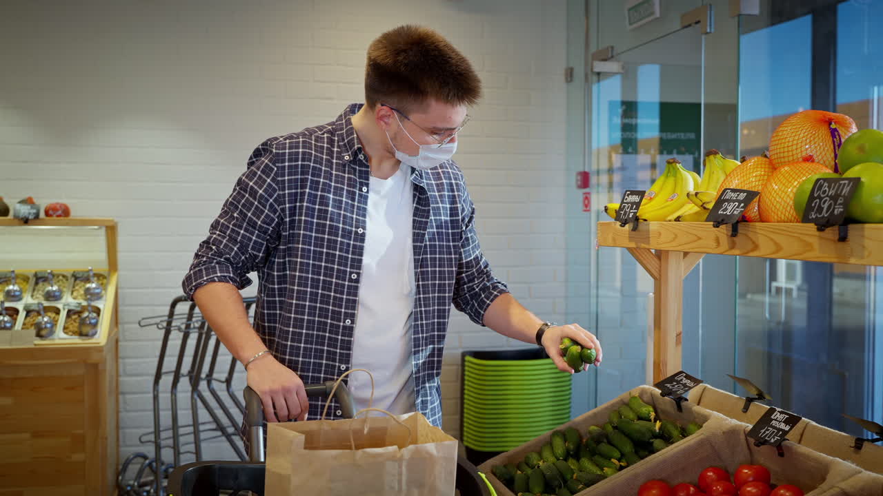 얼굴 마스크를 착용 한 슈퍼마켓에서 식료품을 쇼핑하는 남자
