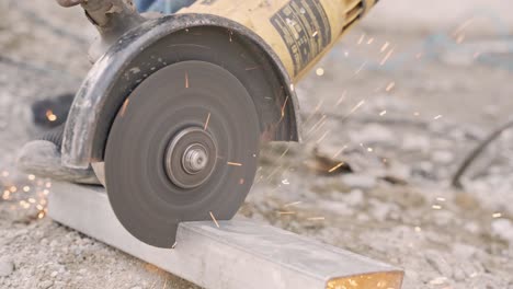 handheld shot of circular electric saw cutting metal surface with sparks