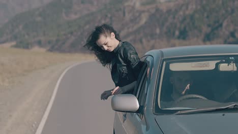 beautiful brunette in leather jacket sits on car window