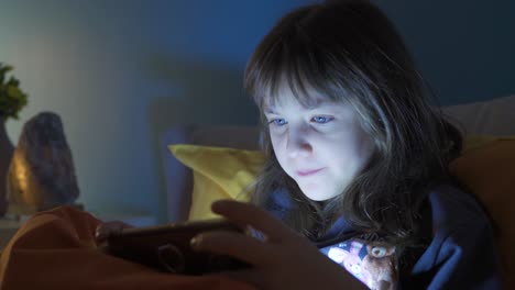 Una-Niña-Adicta-A-La-Tecnología-Juega-Con-El-Teléfono-Por-La-Noche-En-Su-Cama.