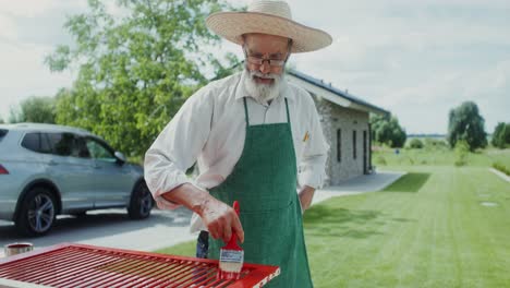 senior man painting wooden fence in garden