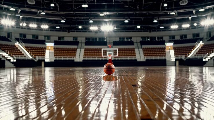 Un pallone da basket su un campo lucido, ripreso da una prospettiva dal basso in un'arena vuota