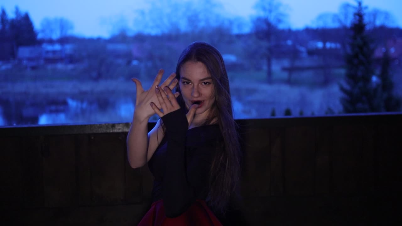 Slow motion female performer dance on a balcony in the evening