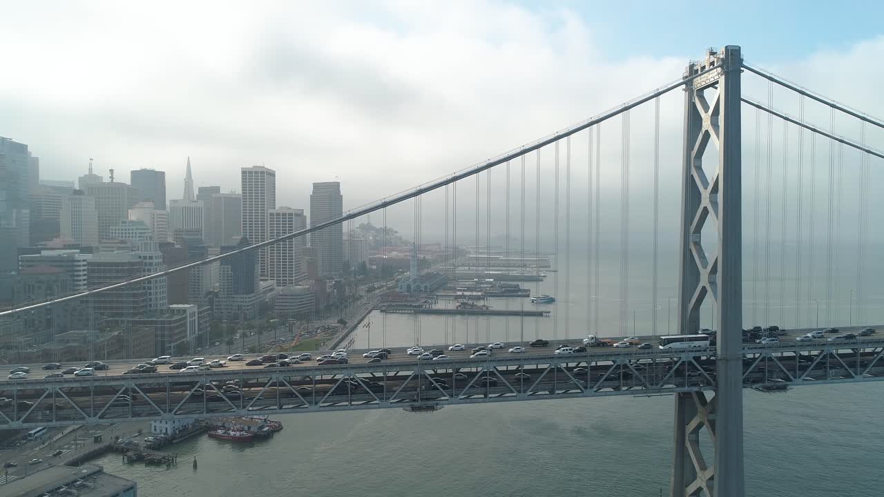 toma aérea de vehículos moviéndose en el puente de la bahía de san francisco–oakland con la ciudad al fondo