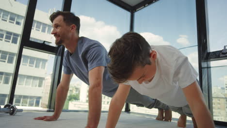 Energy-man-and-boy-pushing-up-at-home.-Father-and-son-having-workout