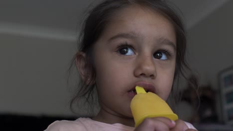 four year old uk asian girl licking and sucking on ice lolly