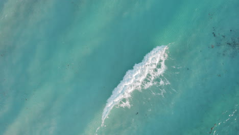 aerial top down shot of rolling waves in a crystal clear blue ocean in cancun mexico