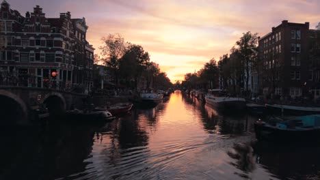 timelapse of stunning orange sunset with a busy canal full of boats in amsterdam