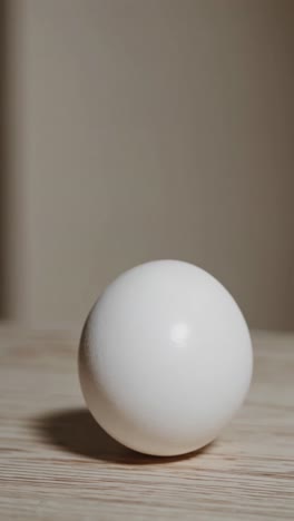 minimalist video concept featuring a single white egg on a wooden surface