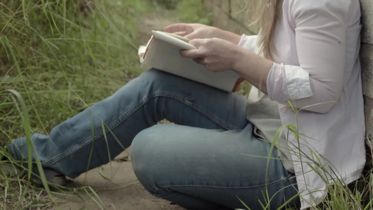 mujer relajándose en el camino del jardín leyendo un libro