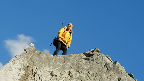 Senior-woman-standing-with-arms-up-on-a-rock-4k