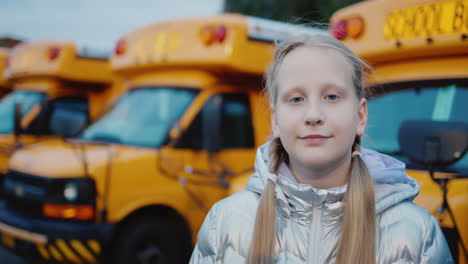 portrait of a schoolgirl against the background of yellow school buses