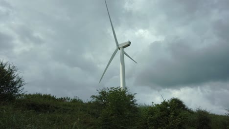 passing shot of turning wind turbine on cloudy day