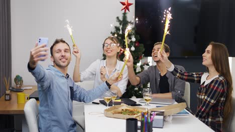 alegres colegas de oficina celebrando la fiesta corporativa navideña, saludando con destellos dorados