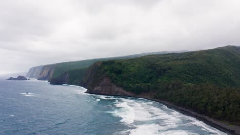steep green cliffs and forested slopes of polulu valley in hawaii tower above rolling blue waves that crash onto the shore, while drifting mist adds a sense of mystery to the rugged coastline.