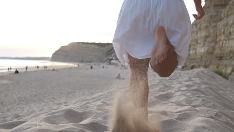 unrecognizable woman running in the summer sunset along the sunny exotic shore in portugal. slow motion, low angle, close-up