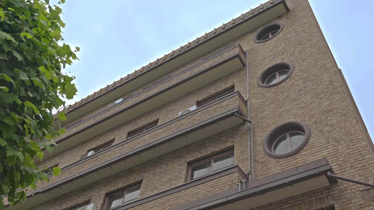 A charming older building in Kuramae, Tokyo, characterized by its brick facade and distinctive circular windows, reflecting the area's blend of history and style.