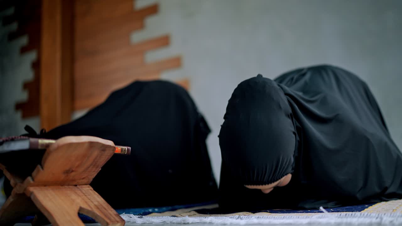 아시아 젊은 무슬림 여성과 여동생이 집에서 기도하고 있습니다.