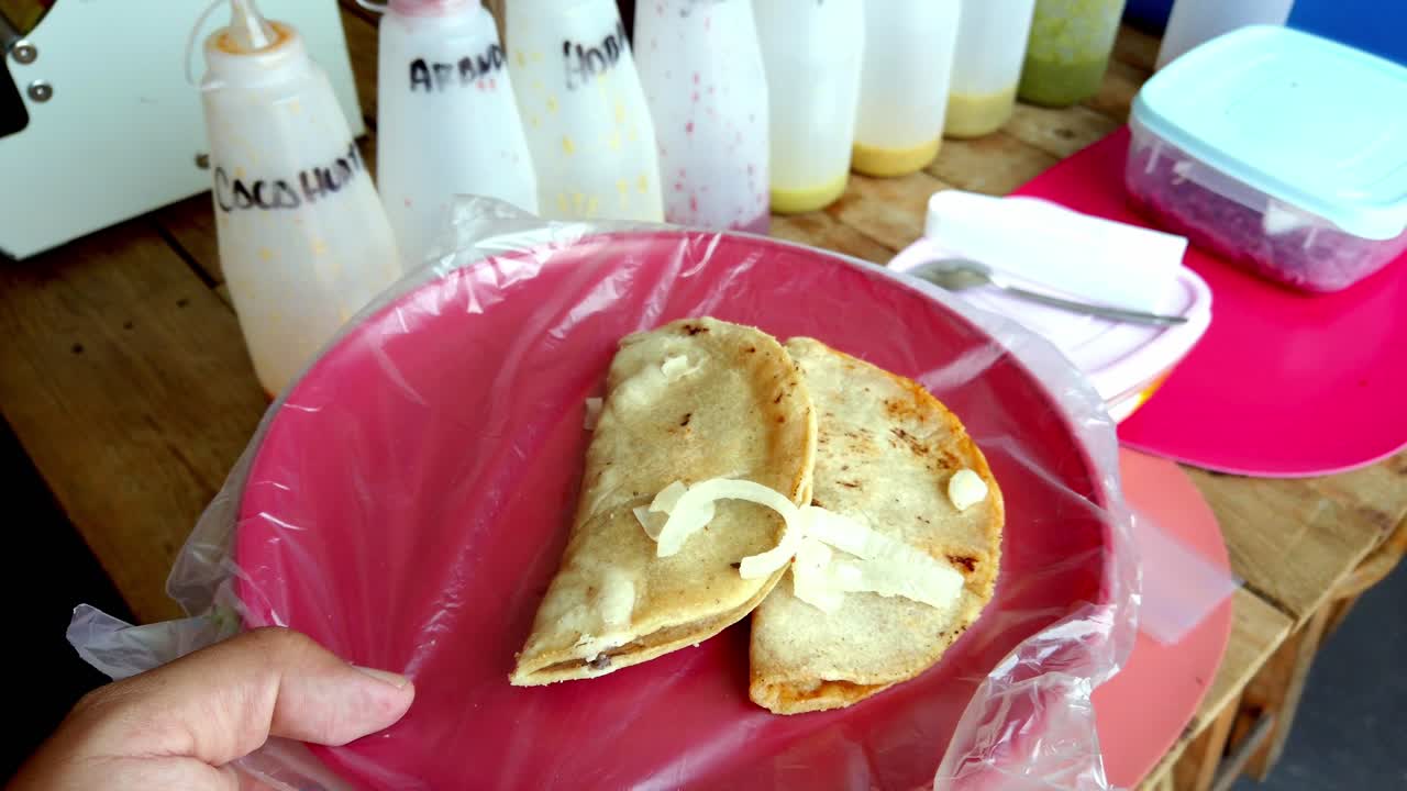 Traditional Mexican taco served on a red plate with onions and plastic cover