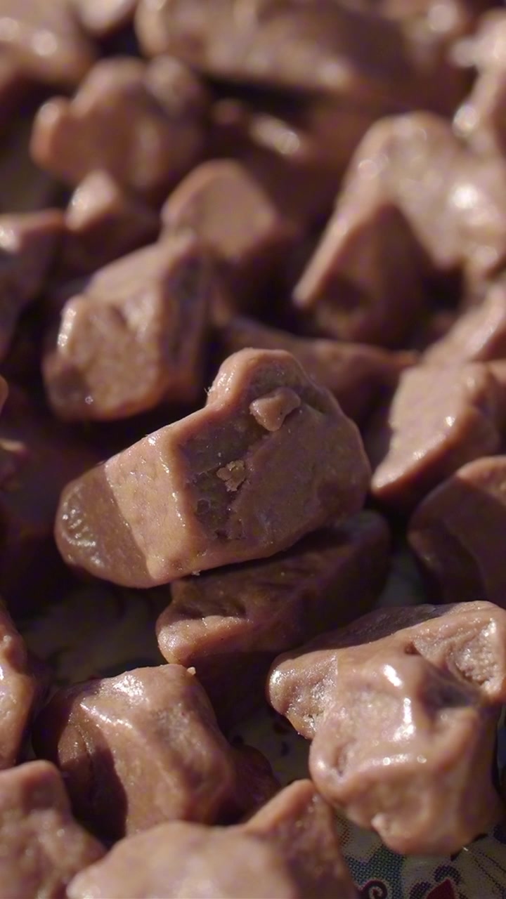 Nahaufnahme von glänzenden braunen Schokoladenbonbons, die herunterfallen