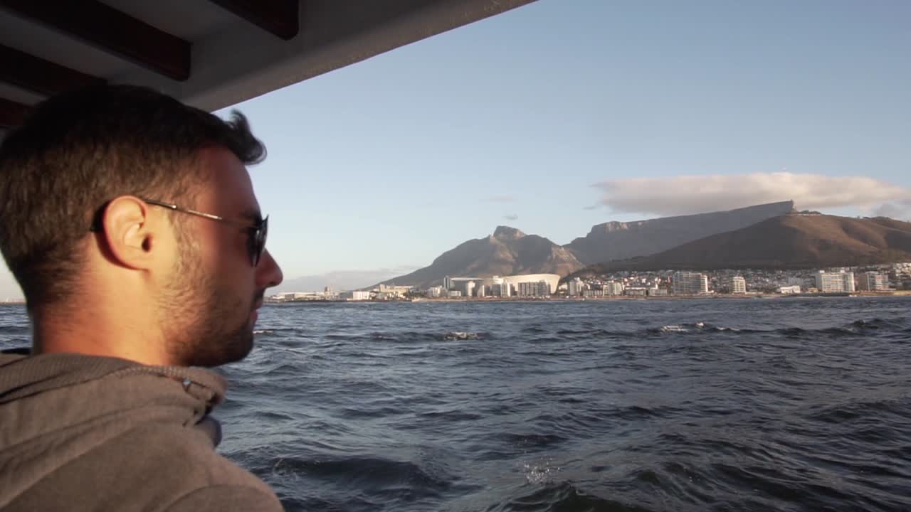 Close up of Man looking at the shore of Cape Town and Table Mountain from the boat in Slow Motion