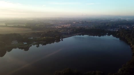 Slow-forward-moving-aerial-over-reservoir,lake-on-sunrise-misty-morning-towards-bridge