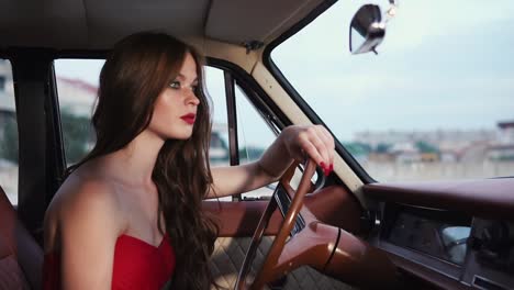 woman in a red dress driving a vintage car