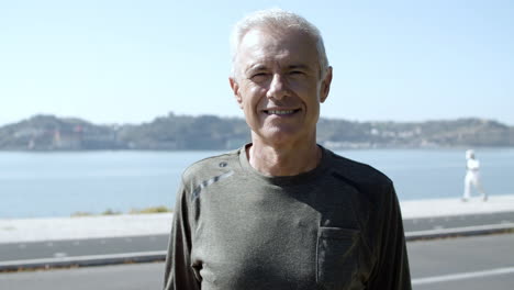 positive active elder 60s man in sportswear standing outdoors