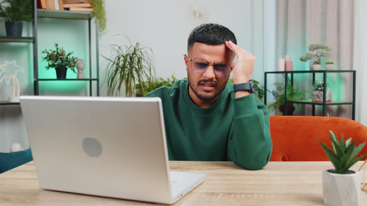 Tired indian man freelancer use laptop suffering from headache problem tension and migraine stress
