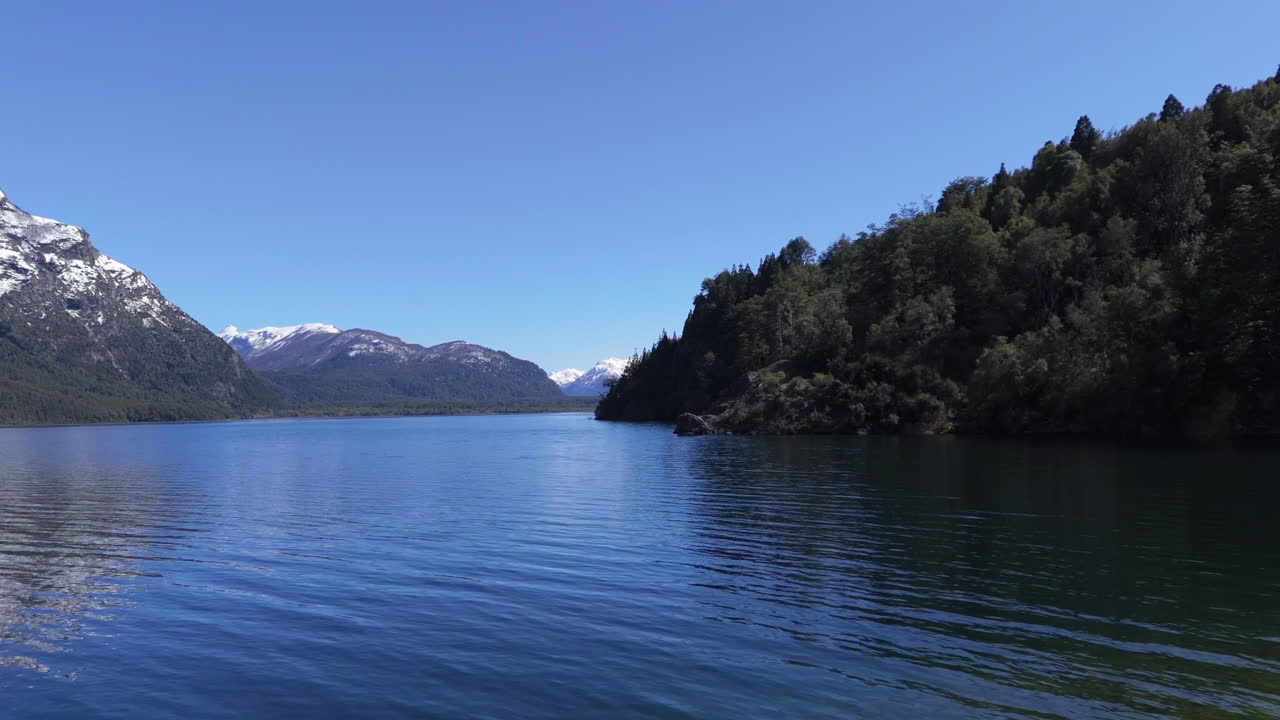 Deep blue waters reflecting snowy mountains and lush vegetation in Lago Futalaufquen, a stunning destination nestled in Parque Nacional Los Alerces in the heart of Argentinian Patagonia, static shot