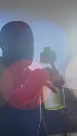 Animation of spots over african american man drinking water outdoors