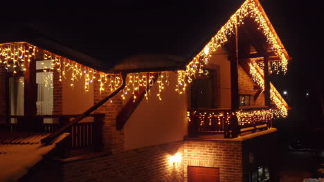 aerial drone shot flying up to home covered in christmas lights at night