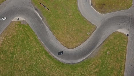 drifting race car on a track going into a s turn, aerial top down shot