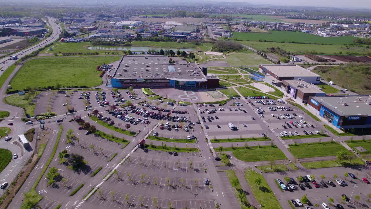 vista aérea por drones de un centro comercial con un enorme estacionamiento al aire libre, autos estacionados y autos en tráfico, gran camino a la izquierda