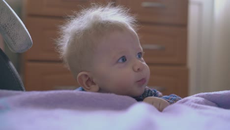 cute-baby-plays-with-tube-leaning-on-bed-with-pink-plaid