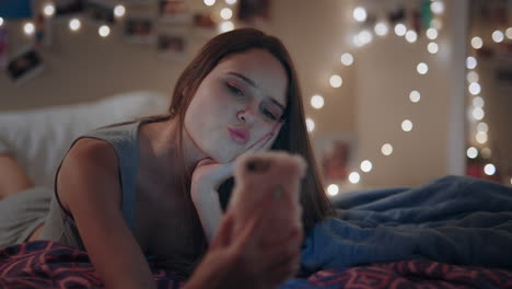 beautiful teenage girl lying on bed texting using smartphone browsing social media online chat enjoying evening relaxing at home