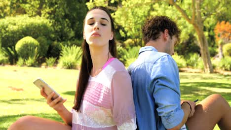 una pareja sentada de espaldas y usando un teléfono inteligente