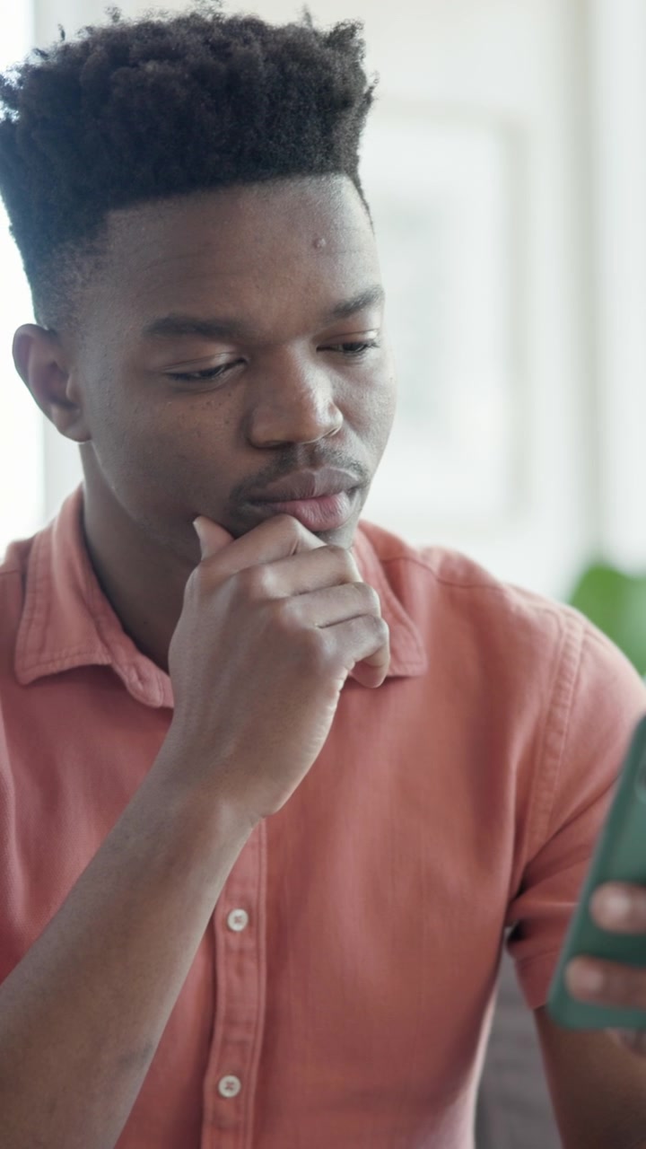 Young Man Looking Thoughtfully at Smartphone Screen