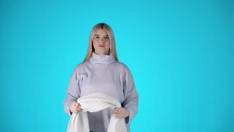 young blonde woman wears a grey woolen scarf, winter clothing, studio portrait